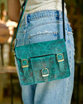 Woman holding a teal satchel handbag with many compartments and utility and aesthetic