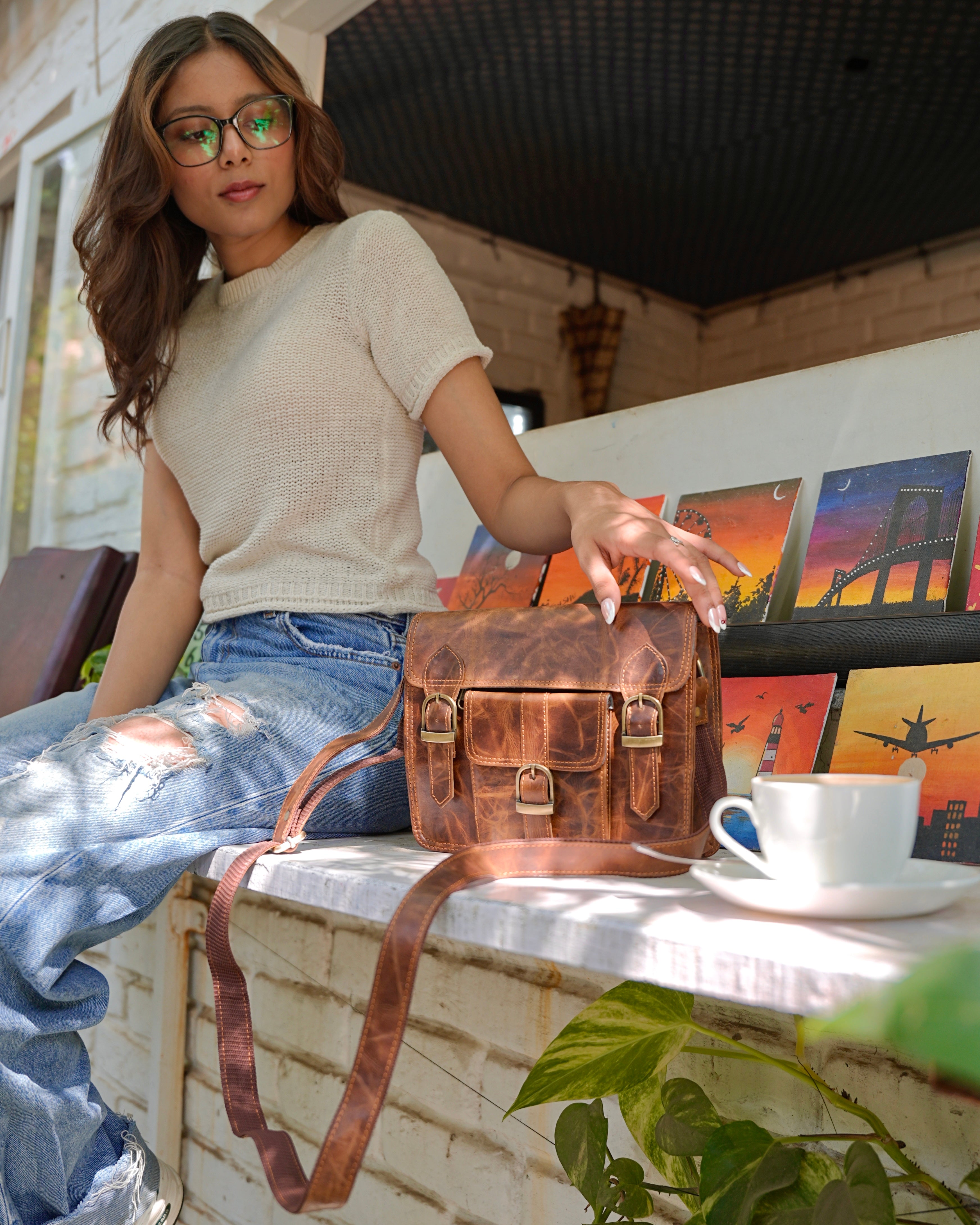 woman holding a brown buffalo leather satchel with multiple compartments and utility