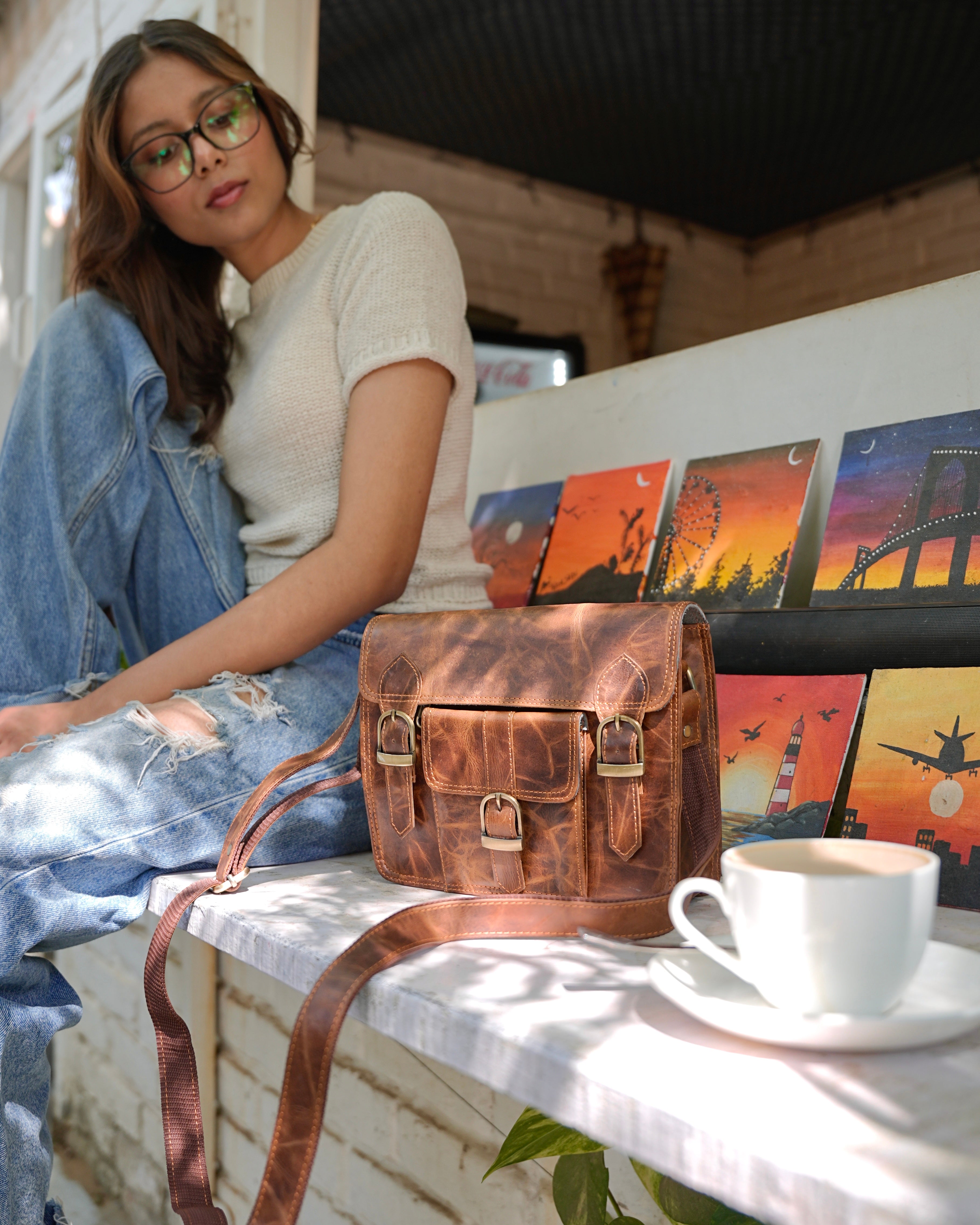woman holding a brown buffalo leather satchel with multiple compartments and utility