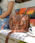 woman holding a brown buffalo leather satchel with multiple compartments and utility