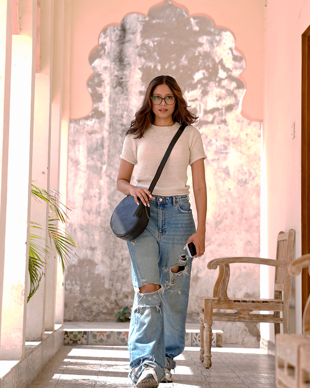 woman holding a black sling crossbody circular aesthetic leather bag
