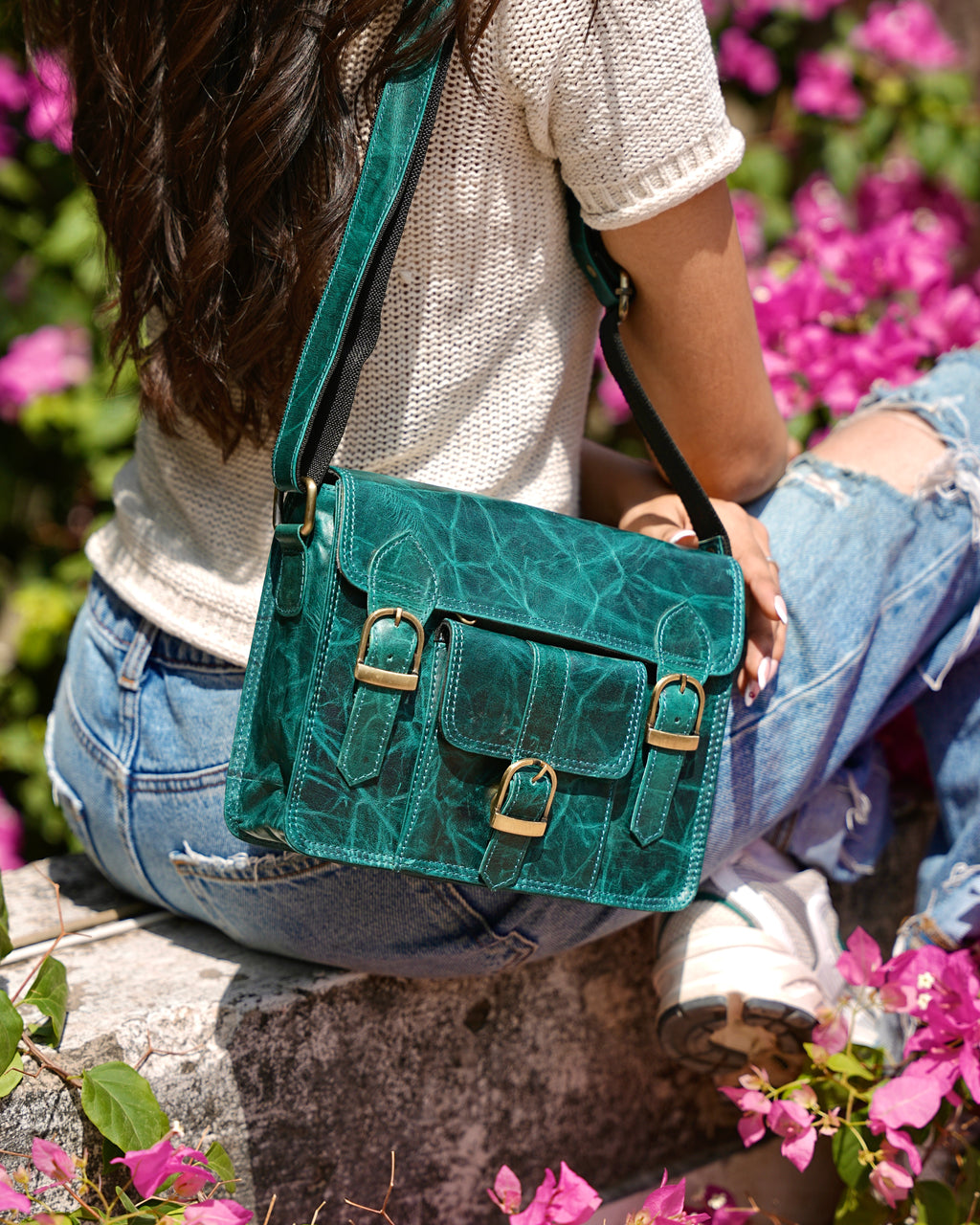 Woman holding a teal satchel handbag with many compartments and utility and aesthetic