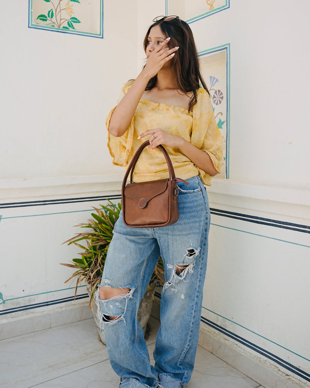 Brown buffalo leather handbag held by a person with a aesthetic background