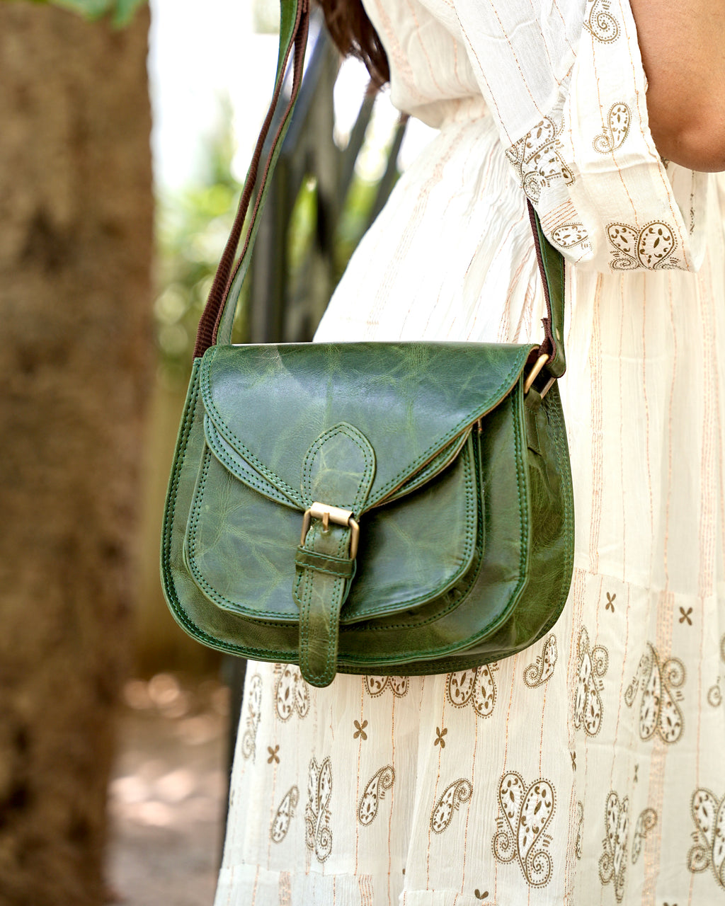 woman holding a green buffalo leather crossbody bag with multiple uses and compartments