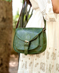 woman holding a green buffalo leather crossbody bag with multiple uses and compartments