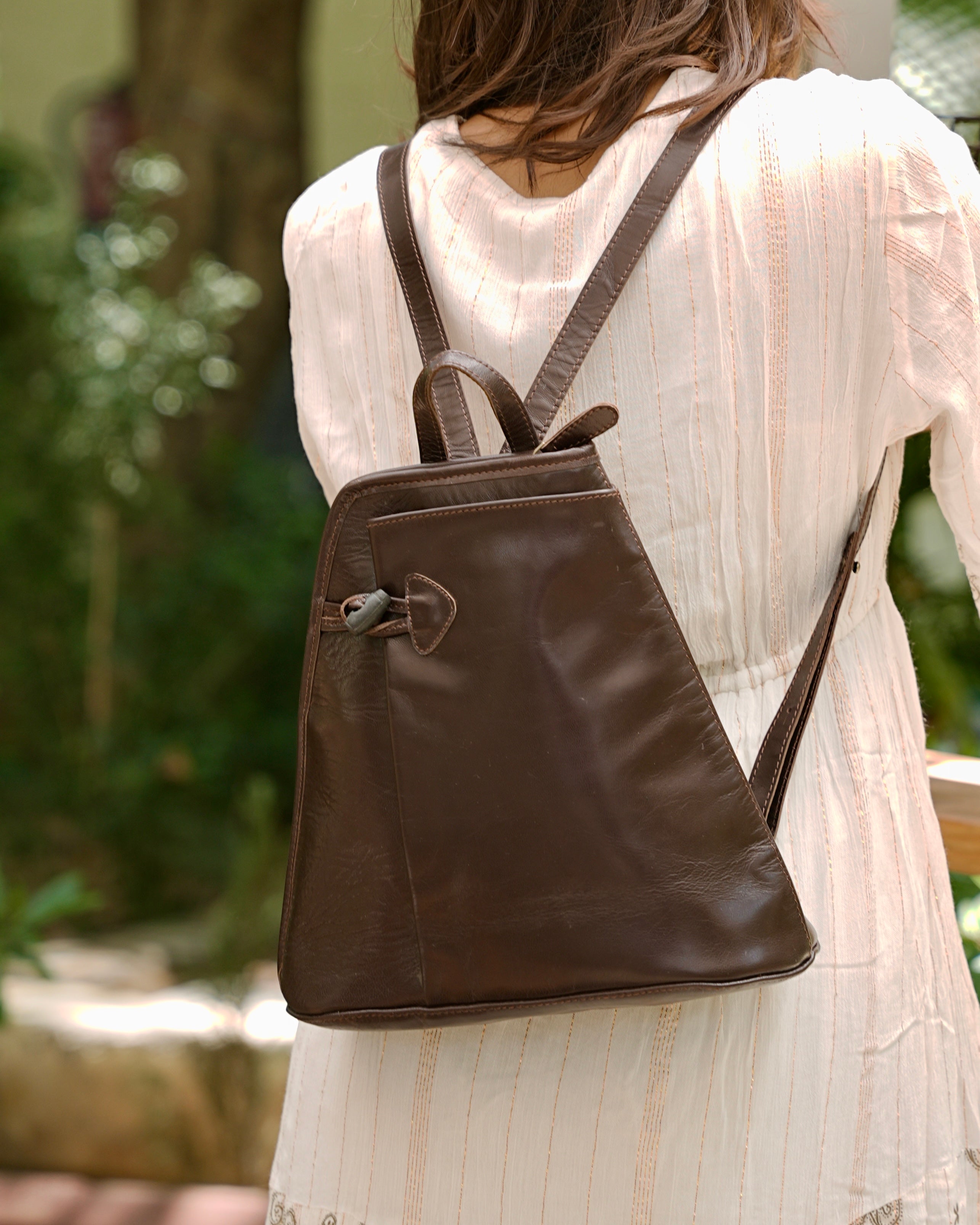 Person wearing a brown buffalo leather backpack with multiple uses and utility