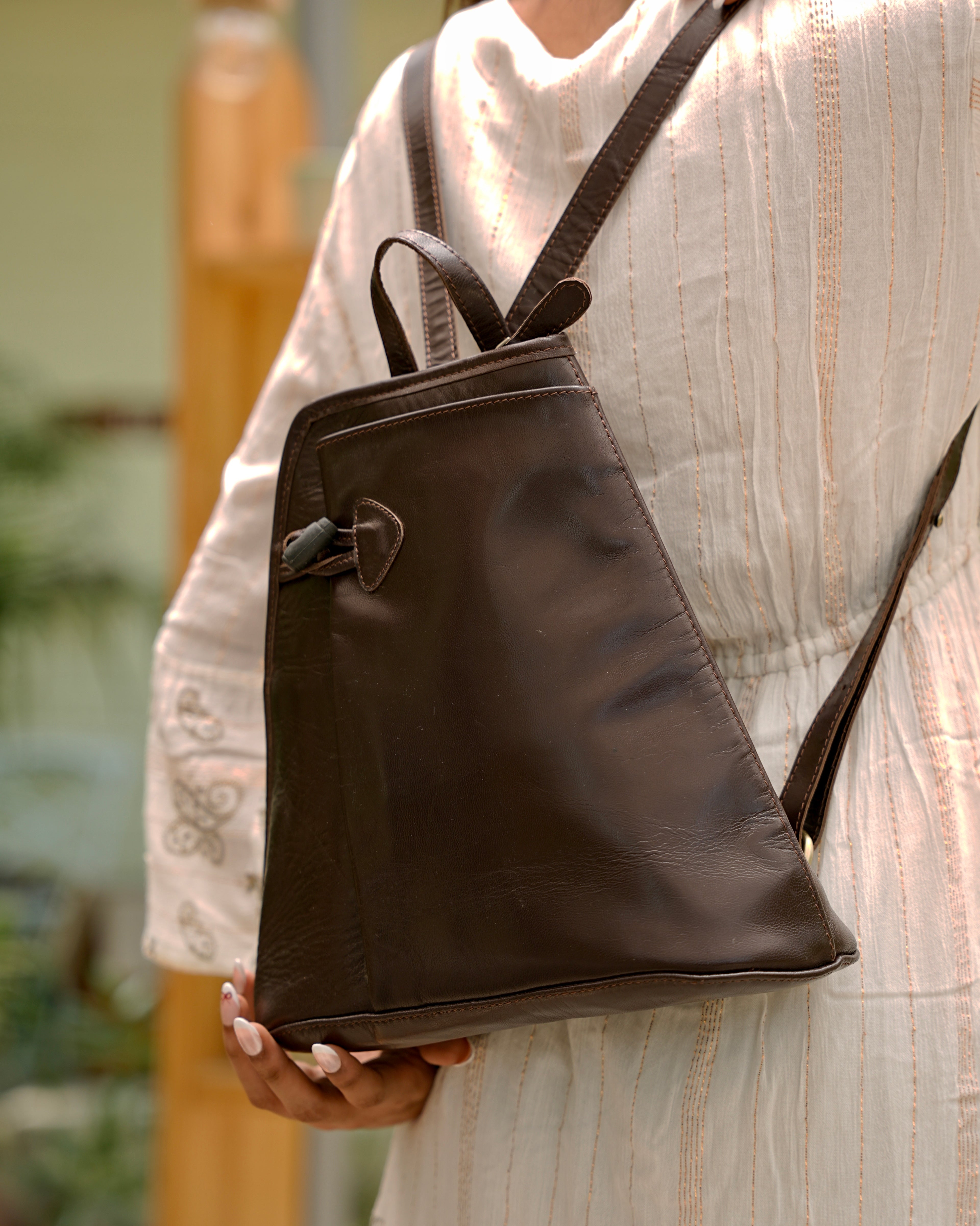 Person wearing a brown buffalo leather backpack with multiple uses and utility