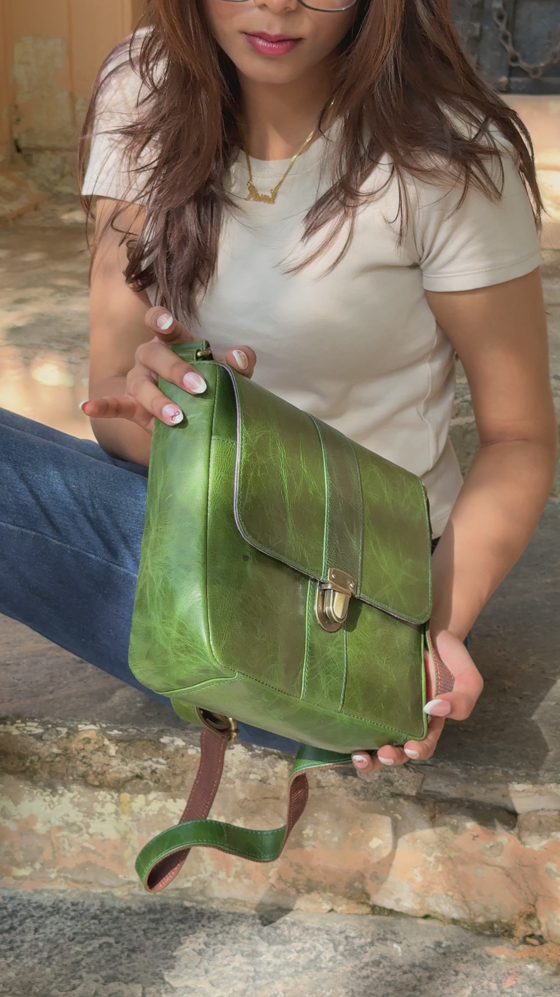 woman holding a green sling bag with multiple compartments and utility and aesthetic