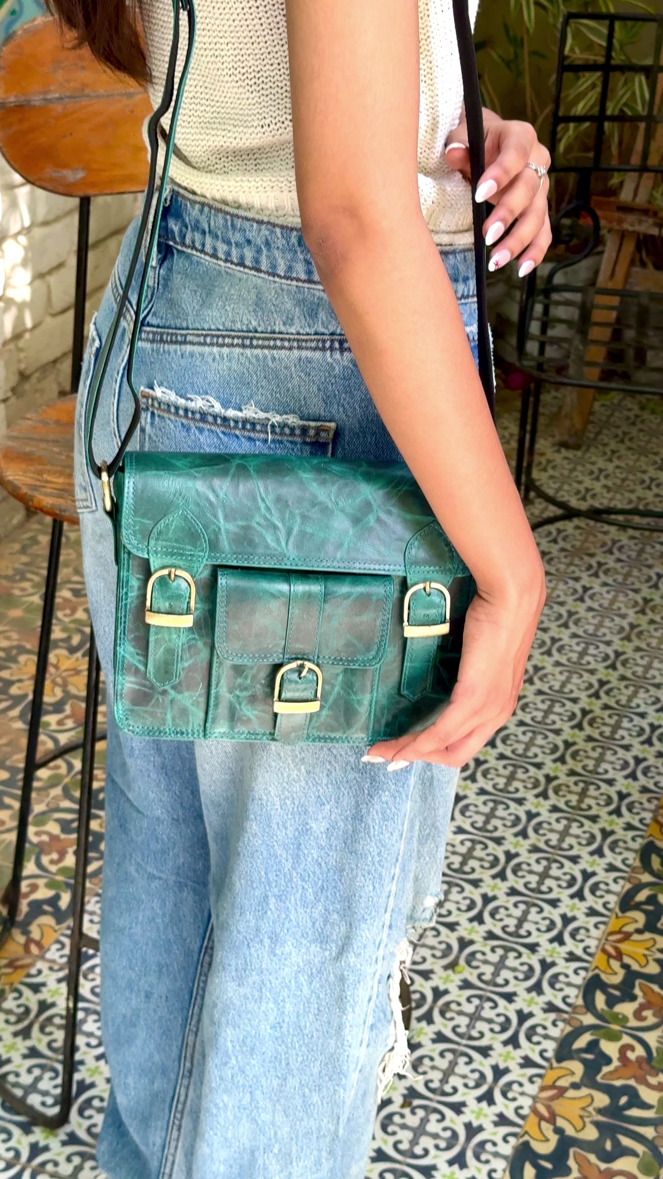 Woman holding a teal satchel handbag with many compartments and utility and aesthetic