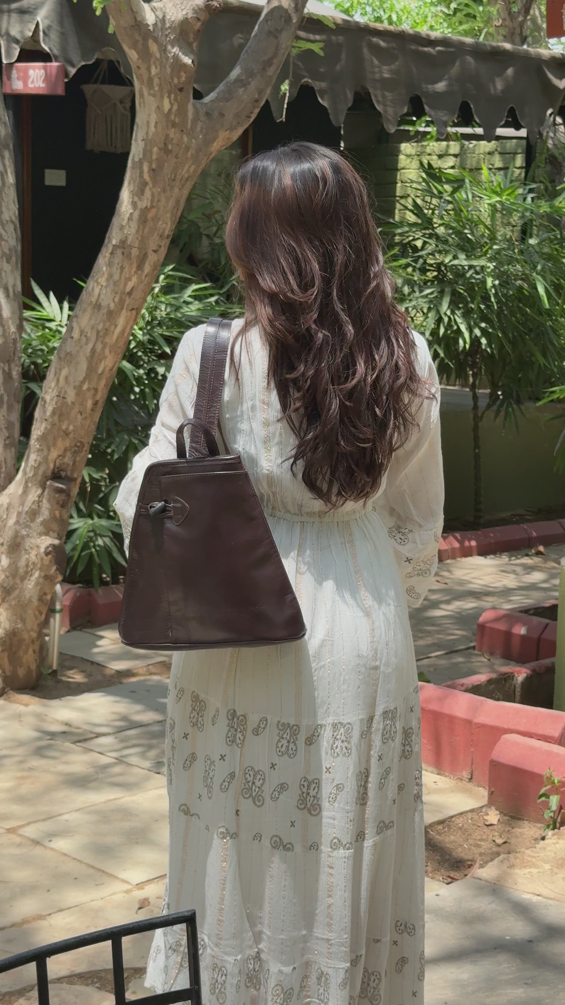 Person wearing a brown buffalo leather backpack with multiple uses and utility