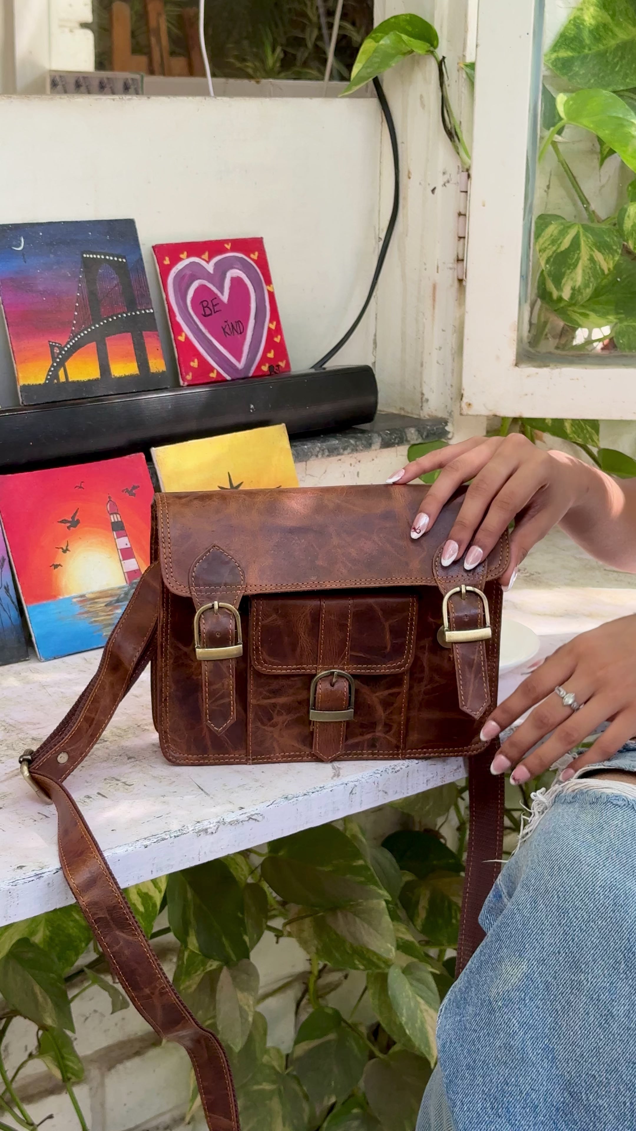 woman holding a brown buffalo leather satchel with multiple compartments and utility
